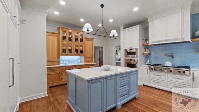 kitchen with appliances with stainless steel finishes, light countertops, a kitchen island, and wood finished floors