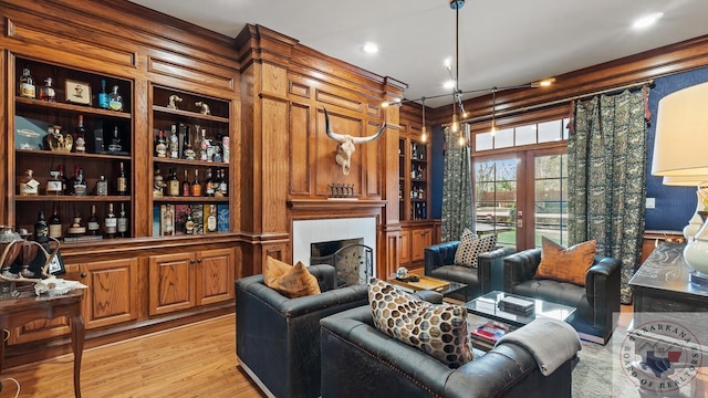 living area featuring light wood-style flooring, built in shelves, french doors, and a tile fireplace