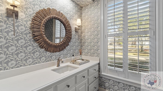 bathroom featuring plenty of natural light, vanity, and wallpapered walls