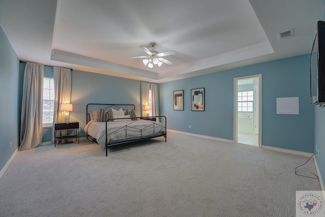 carpeted bedroom featuring connected bathroom, ceiling fan, and a raised ceiling