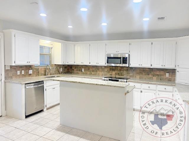 kitchen with sink, white cabinetry, stainless steel appliances, and a kitchen island