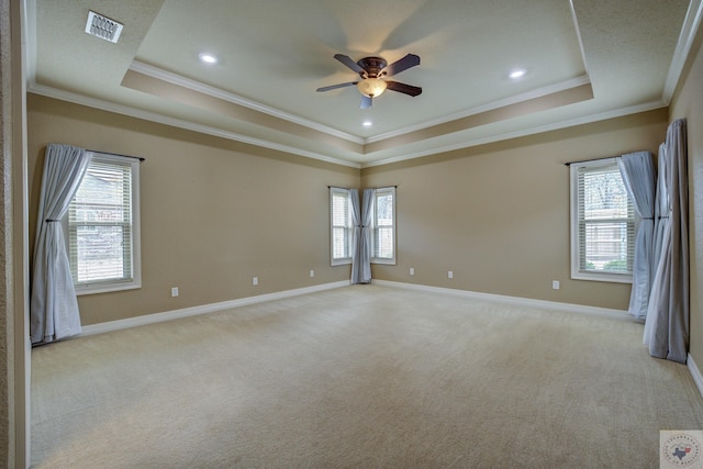 empty room with baseboards, a raised ceiling, visible vents, and light colored carpet
