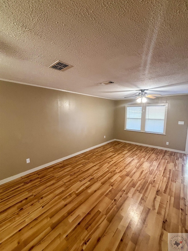 empty room with light wood-type flooring, ceiling fan, and a textured ceiling