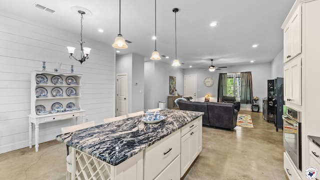 kitchen featuring concrete floors, visible vents, ceiling fan with notable chandelier, and stainless steel oven