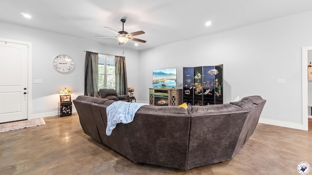 living area featuring concrete floors, baseboards, a lit fireplace, recessed lighting, and ceiling fan