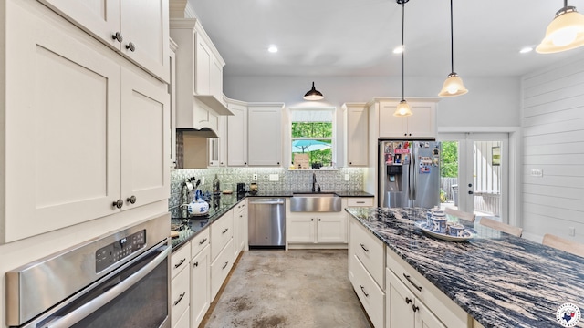kitchen with hanging light fixtures, decorative backsplash, a sink, and stainless steel appliances