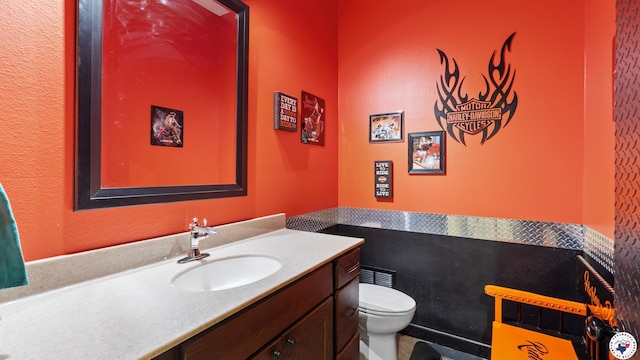 half bath featuring vanity and toilet