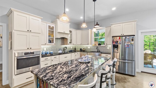 kitchen with a sink, decorative backsplash, white cabinets, and stainless steel appliances
