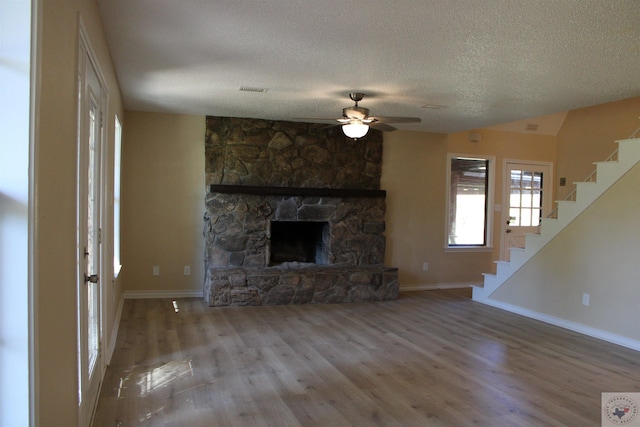 unfurnished living room featuring ceiling fan, a textured ceiling, a fireplace, and hardwood / wood-style floors