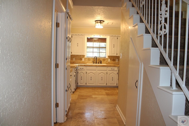 hall featuring sink, a textured ceiling, and ornamental molding