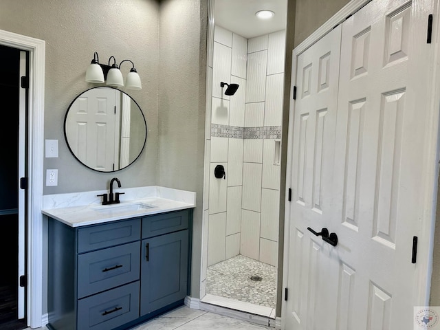 bathroom with a tile shower and vanity