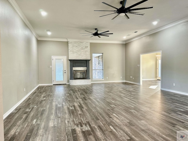 unfurnished living room featuring ceiling fan, dark wood-type flooring, ornamental molding, and a fireplace