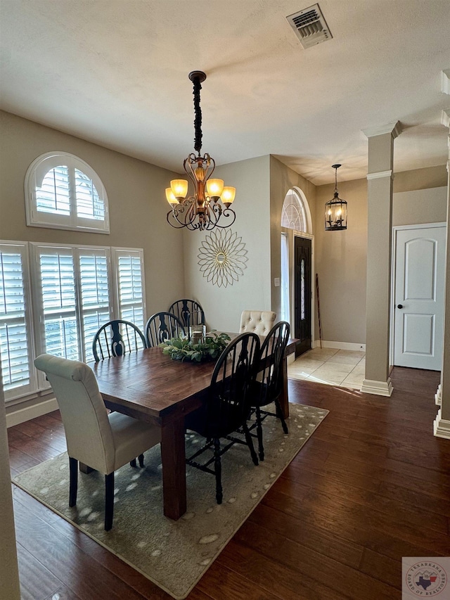 dining space featuring a chandelier, visible vents, baseboards, and wood finished floors