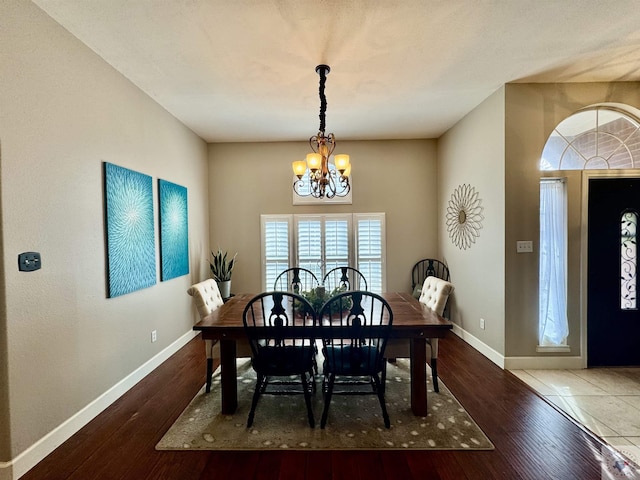 dining area featuring baseboards, an inviting chandelier, and hardwood / wood-style floors