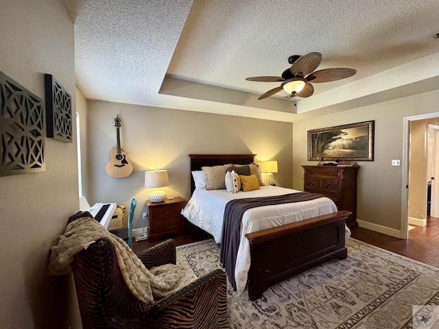 bedroom featuring a tray ceiling, wood finished floors, and a textured ceiling