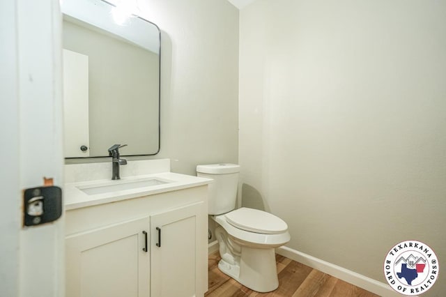 bathroom with baseboards, vanity, toilet, and wood finished floors