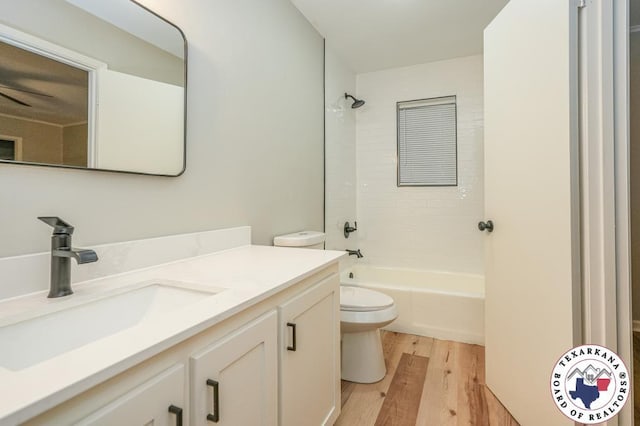 bathroom featuring toilet, tub / shower combination, wood finished floors, and vanity