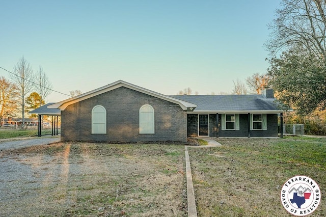 ranch-style home featuring a chimney, a front lawn, and brick siding