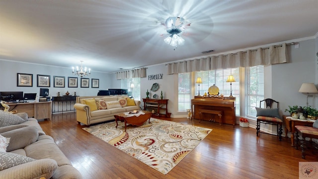 living room featuring wood-type flooring, crown molding, and an inviting chandelier