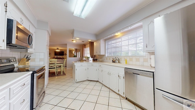 kitchen with light tile patterned flooring, sink, white cabinetry, stainless steel appliances, and decorative backsplash