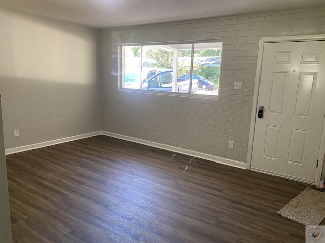 foyer featuring dark wood-type flooring and brick wall