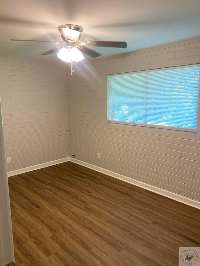 unfurnished room with ceiling fan, dark wood-type flooring, brick wall, and crown molding