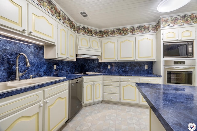803 Lakeridge Pl, Texarkana, TX 75503 - kitchen featuring appliances with stainless steel finishes, cream cabinets, a sink, dark countertops, and backsplash