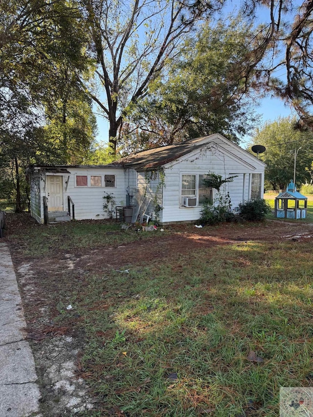 view of front of home featuring cooling unit and a front yard