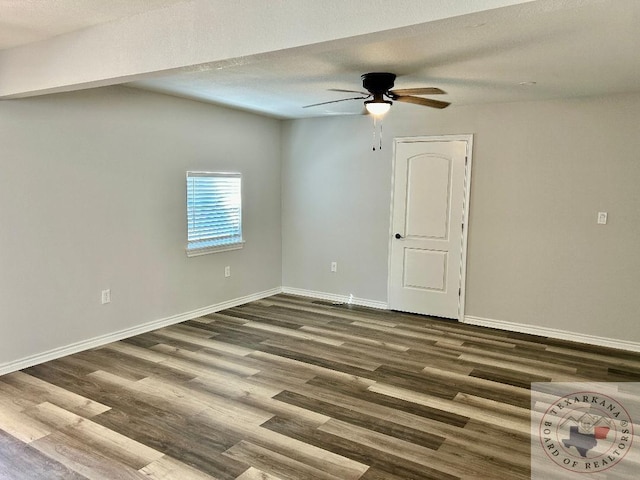 spare room featuring ceiling fan, dark wood-type flooring, and a textured ceiling