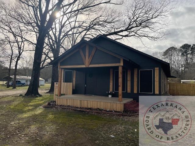 view of front of house featuring covered porch and fence