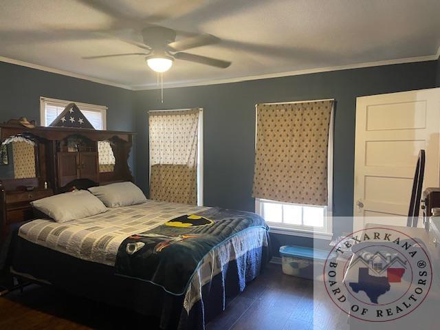 bedroom featuring dark hardwood / wood-style flooring, ceiling fan, and ornamental molding