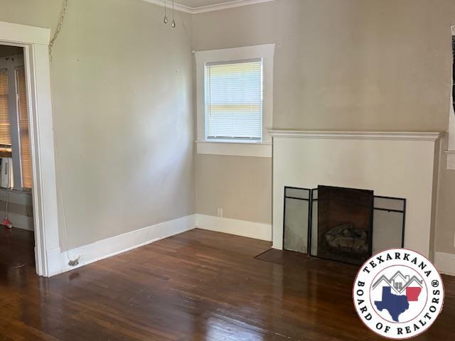 2308 Laurel St, Texarkana, AR 71854 - unfurnished living room featuring wood finished floors, ornamental molding, and a fireplace with flush hearth