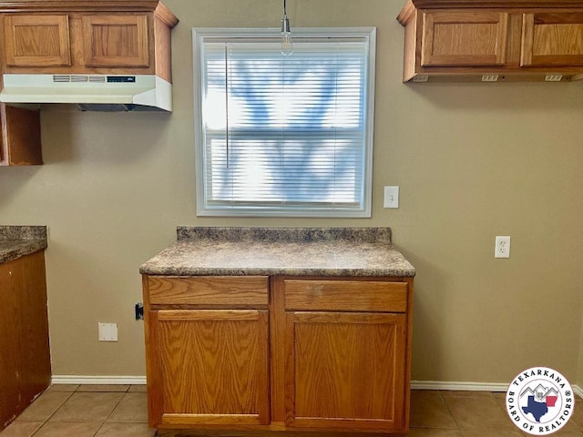 704 Florence St, Atlanta, TX 75551 - kitchen featuring under cabinet range hood, light tile patterned floors, baseboards, and dark countertops