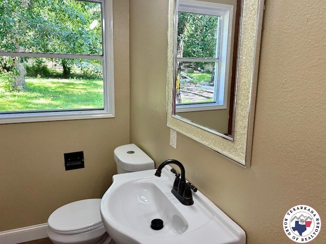 704 Florence St, Atlanta, TX 75551 - bathroom featuring a sink, toilet, and a textured wall