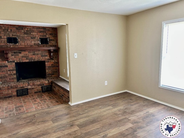 704 Florence St, Atlanta, TX 75551 - unfurnished living room with wood finished floors, baseboards, and a brick fireplace