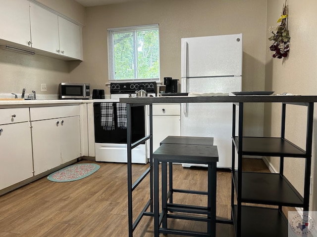 kitchen with white cabinetry, white fridge, and electric range