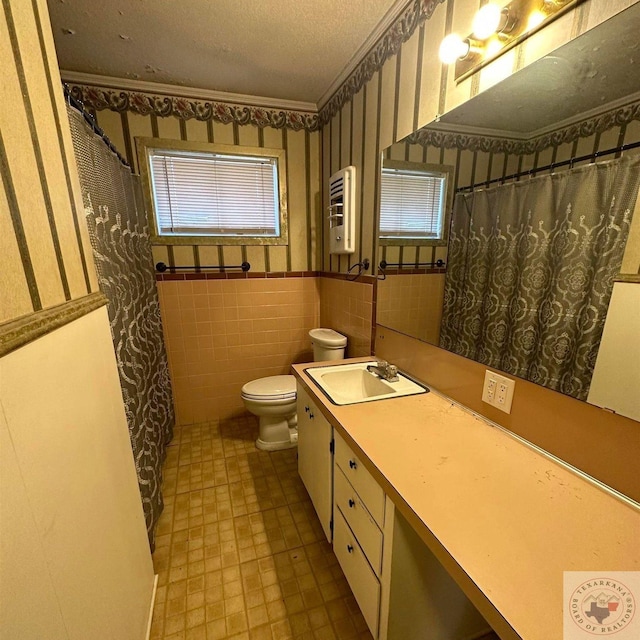 bathroom with vanity, toilet, tile walls, and a textured ceiling