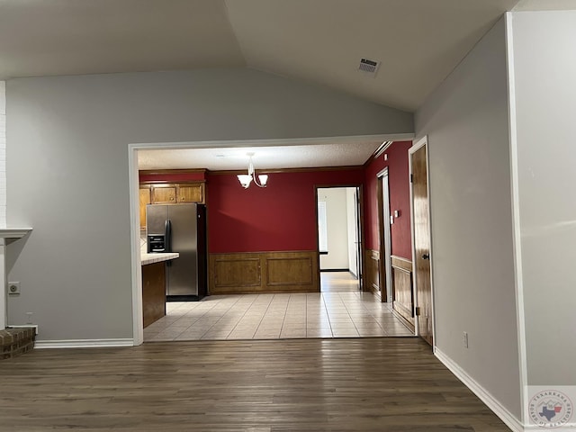 interior space with light hardwood / wood-style floors, vaulted ceiling, and a notable chandelier