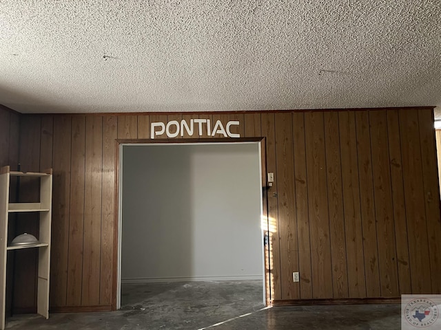 interior space with a textured ceiling and wooden walls