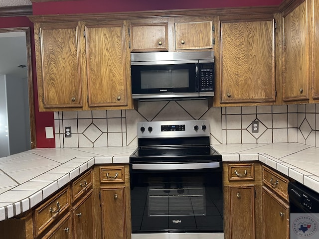 kitchen with decorative backsplash, electric range oven, dishwasher, and tile countertops