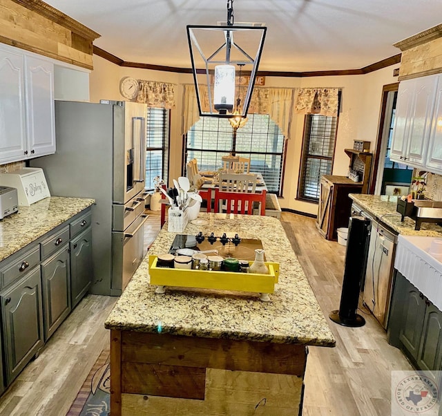 kitchen with decorative light fixtures, white cabinetry, ornamental molding, and light hardwood / wood-style floors