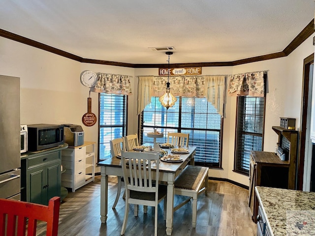 dining space with dark wood-type flooring, a textured ceiling, crown molding, and a chandelier