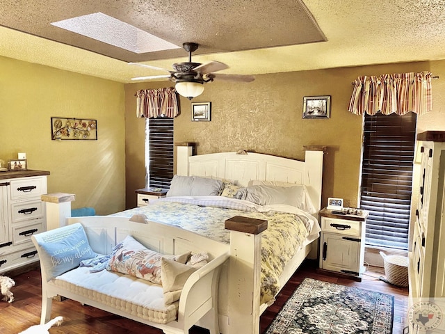 bedroom featuring ceiling fan, a textured ceiling, dark hardwood / wood-style floors, and a skylight