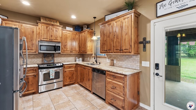 kitchen featuring decorative backsplash, stainless steel appliances, light stone counters, and a sink