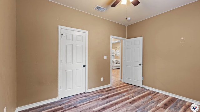 unfurnished bedroom with baseboards, visible vents, a ceiling fan, and wood finished floors