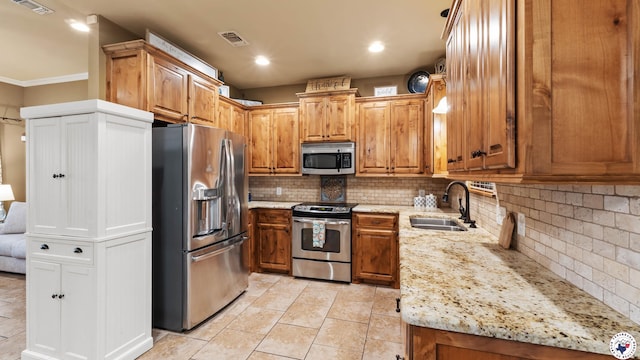 kitchen featuring decorative backsplash, stainless steel appliances, light stone countertops, and a sink