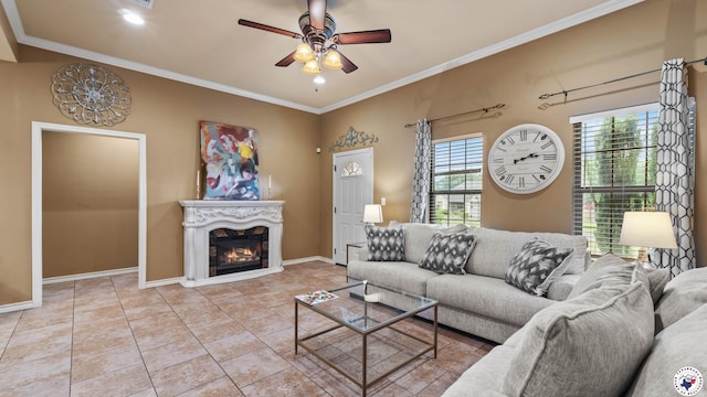 tiled living area featuring ceiling fan, ornamental molding, baseboards, and a glass covered fireplace