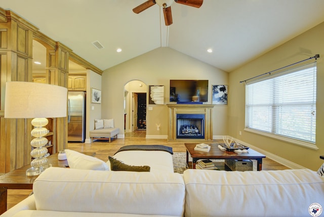 3428 Garrett Ln, Texarkana, TX 75503 - living area featuring ceiling fan, a fireplace, vaulted ceiling, light wood-style flooring, and arched walkways