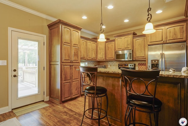 3428 Garrett Ln, Texarkana, TX 75503 - kitchen with appliances with stainless steel finishes, tasteful backsplash, wood finished floors, a kitchen breakfast bar, and ornamental molding