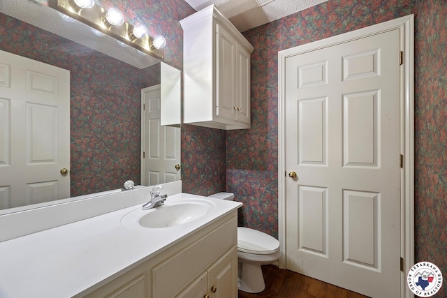 6102 Deerfield Dr, Texarkana, TX 75503 - bathroom with wood finished floors, wallpapered walls, vanity, and toilet